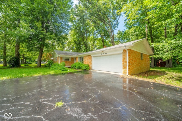 10104 Sycamore Ln, Indianapolis, IN 46239 - view of front facade featuring driveway, brick siding, an attached garage, a front yard, and view of wooded area