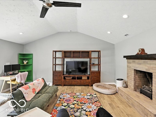 11093 N Pheasant Run, Fairland, IN 46126 - living area with light wood-style floors, lofted ceiling, ceiling fan, a textured ceiling, and a fireplace