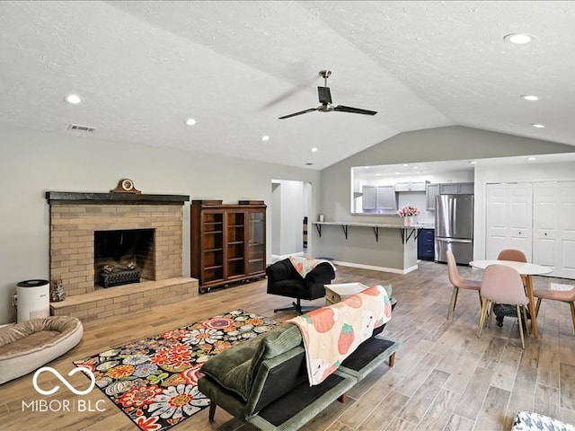 11093 N Pheasant Run, Fairland, IN 46126 - living room featuring light wood-style floors, a ceiling fan, lofted ceiling, a textured ceiling, and a fireplace