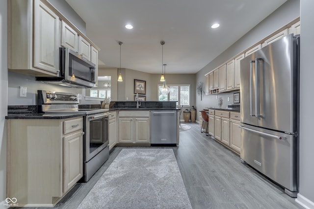1454 Heron Ridge Blvd, Greenwood, IN 46143 - kitchen featuring appliances with stainless steel finishes, a peninsula, dark countertops, light wood-style floors, and recessed lighting