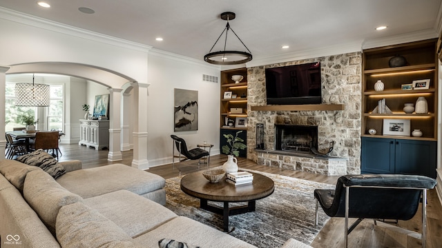 9681 Pleasant View Ln, Zionsville, IN 46077 - living room featuring decorative columns, ornamental molding, wood finished floors, built in shelves, and a stone fireplace