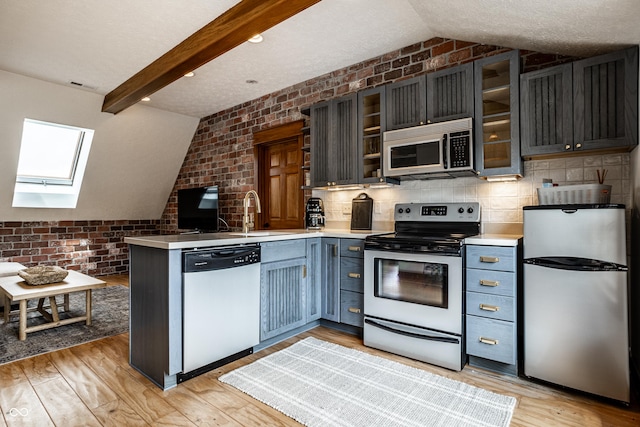9681 Pleasant View Ln, Zionsville, IN 46077 - kitchen featuring stainless steel appliances, a peninsula, a skylight, glass insert cabinets, and light countertops