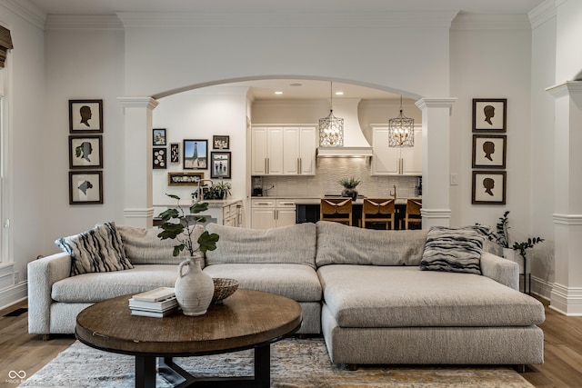 9681 Pleasant View Ln, Zionsville, IN 46077 - living room with arched walkways, wood finished floors, ornamental molding, a chandelier, and ornate columns