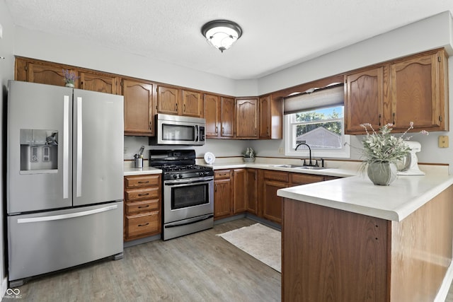 1011 Stevedon Ct, Plainfield, IN 46168 - kitchen featuring appliances with stainless steel finishes, light wood-type flooring, light countertops, and brown cabinetry