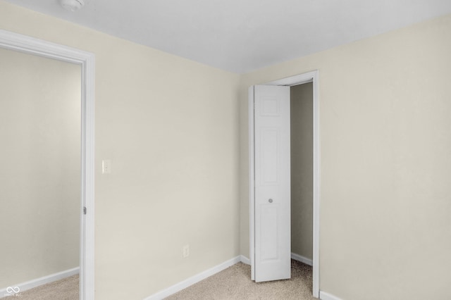 unfurnished bedroom featuring light carpet and baseboards