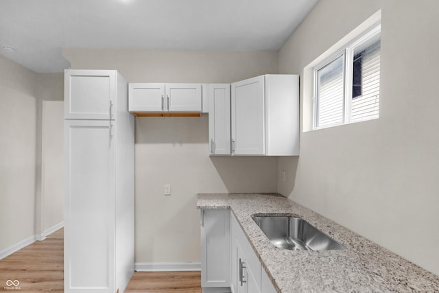 kitchen featuring white cabinets, light stone counters, and light wood-style floors