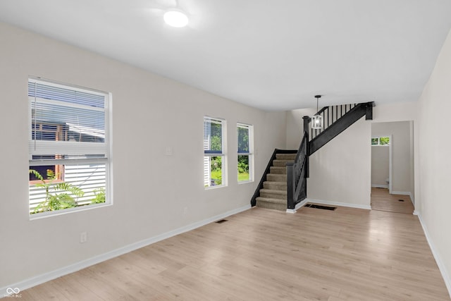 unfurnished living room featuring stairs and light wood finished floors