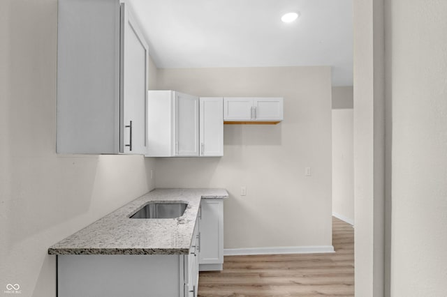 kitchen featuring light stone countertops, white cabinetry, and light wood finished floors
