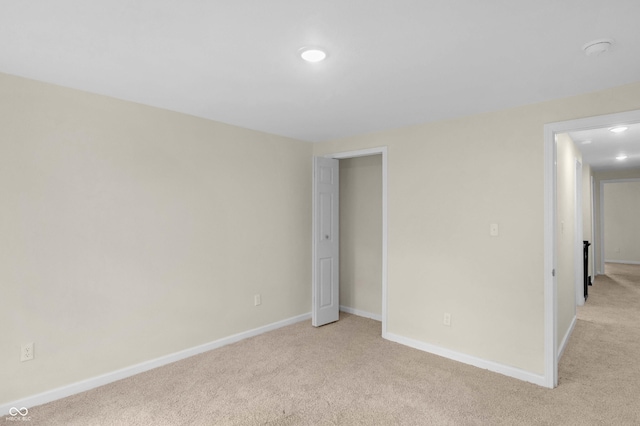 unfurnished bedroom featuring light carpet and baseboards