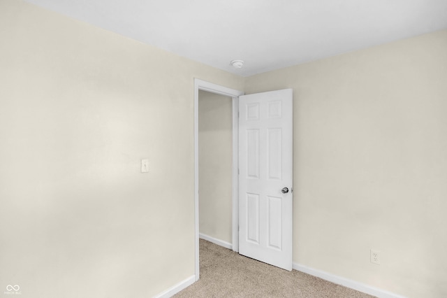 empty room featuring light colored carpet and a smoke detector
