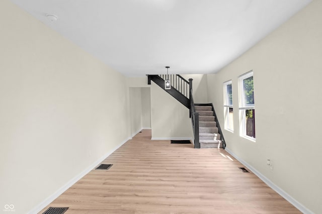 unfurnished living room with stairway and light wood-style flooring