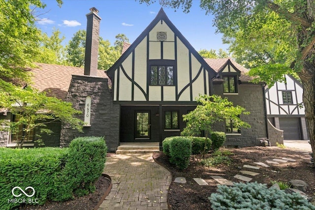 6470 Around The Hills Rd, Indianapolis, IN 46226 - view of front facade with stucco siding, stone siding, a chimney, and roof with shingles
