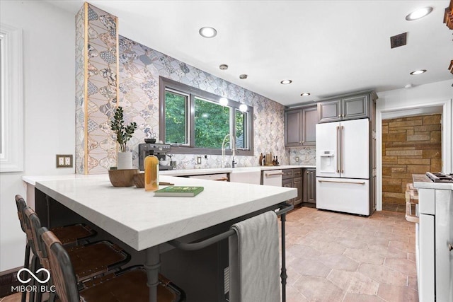 6470 Around The Hills Rd, Indianapolis, IN 46226 - kitchen with white fridge with ice dispenser, a peninsula, a kitchen breakfast bar, recessed lighting, and wallpapered walls