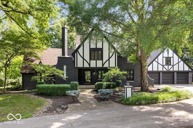 6470 Around The Hills Rd, Indianapolis, IN 46226 - tudor house with a chimney, concrete driveway, and stone siding