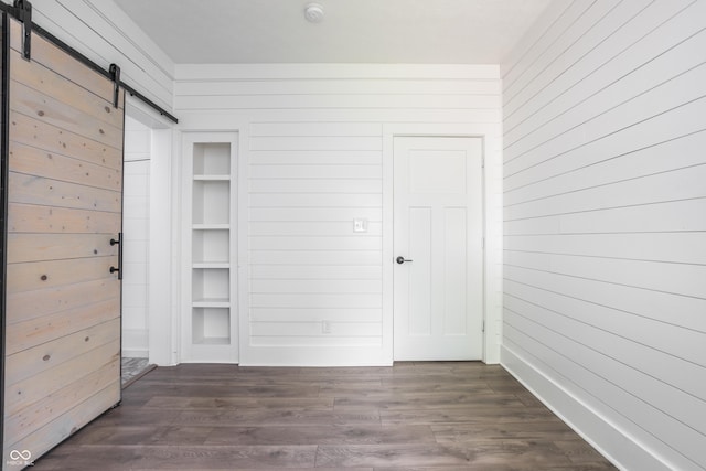 1456 Fletcher Ave, Indianapolis, IN 46203 - unfurnished bedroom with a barn door, wood walls, and dark wood-style floors