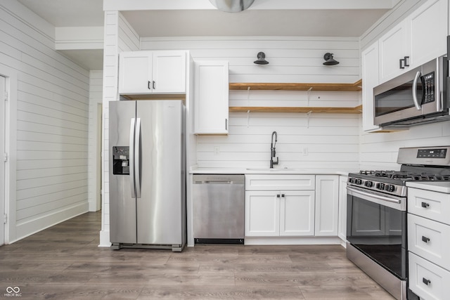 1456 Fletcher Ave, Indianapolis, IN 46203 - kitchen with stainless steel appliances, open shelves, wood walls, white cabinets, and light wood-type flooring