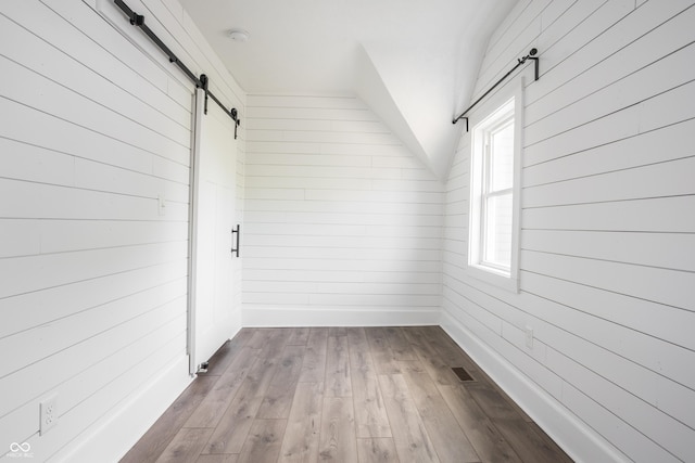 1456 Fletcher Ave, Indianapolis, IN 46203 - additional living space featuring a barn door, wood walls, dark wood-style flooring, and vaulted ceiling