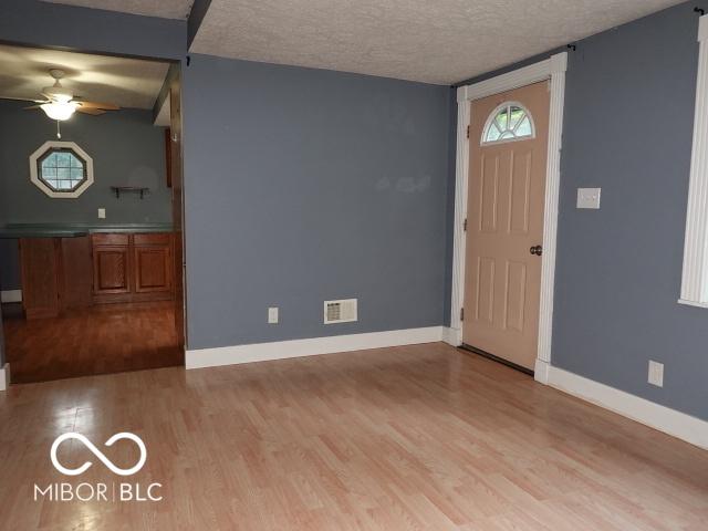 entrance foyer featuring ceiling fan, light wood-style flooring, and a textured ceiling