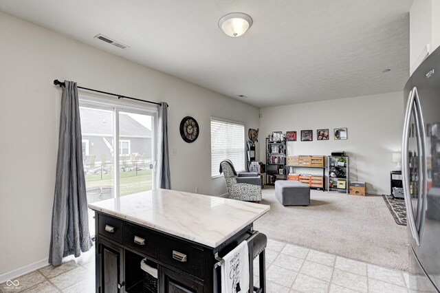 1270 W Limestone Way, Fortville, IN 46040 - kitchen featuring dark cabinetry, freestanding refrigerator, open floor plan, a center island, and light stone counters