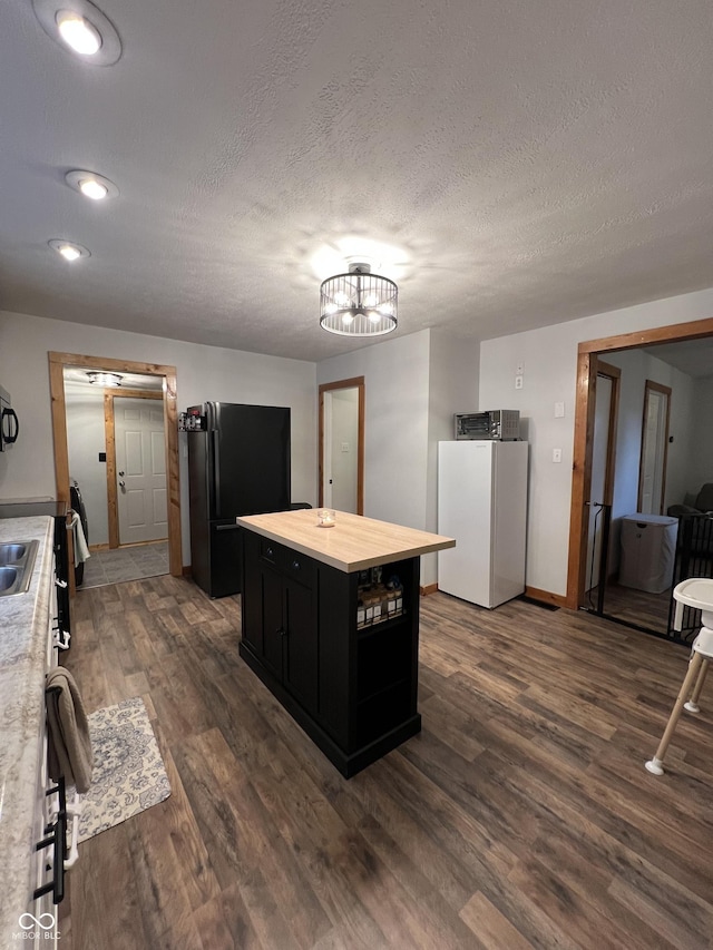 1203 S 6th St, Clinton, IN 47842 - kitchen with dark cabinets, freestanding refrigerator, dark wood-style flooring, a textured ceiling, and a kitchen island