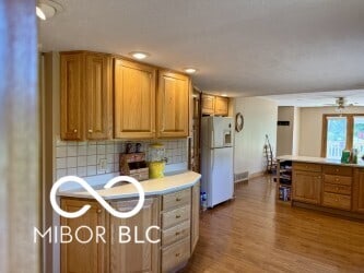 4680 Cartersburg Rd, Plainfield, IN 46168 - kitchen featuring freestanding refrigerator, light countertops, backsplash, wood finished floors, and brown cabinetry