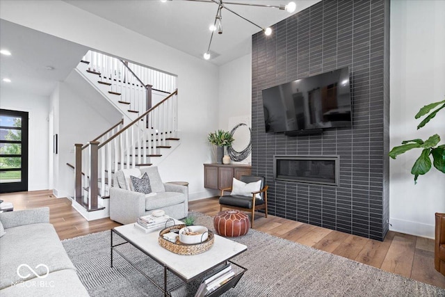 20440 Chatham Hills Blvd, Westfield, IN 46074 - living area with stairway, wood finished floors, a tiled fireplace, a towering ceiling, and recessed lighting