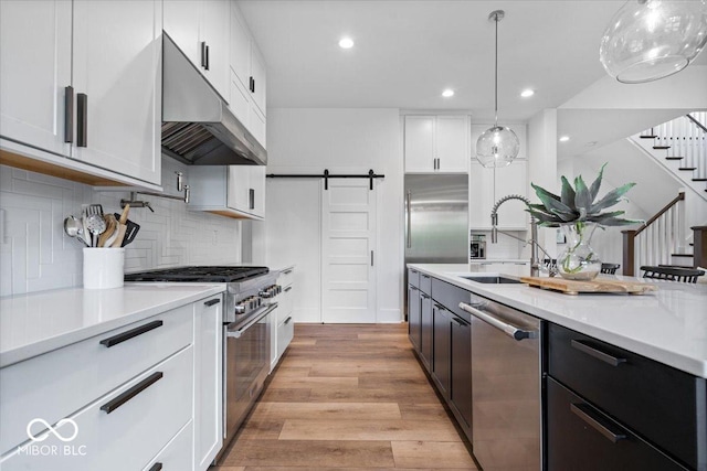 20440 Chatham Hills Blvd, Westfield, IN 46074 - kitchen featuring high end appliances, under cabinet range hood, a barn door, light countertops, and white cabinetry