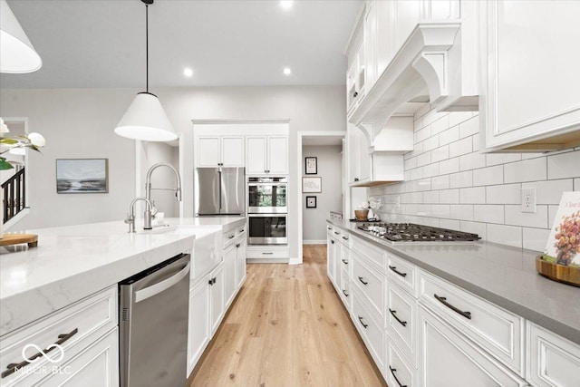 2840 Flowing Creek Pl, Westfield, IN 46074 - kitchen featuring stainless steel appliances, white cabinets, backsplash, light stone counters, and light wood-style flooring