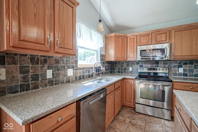 1804 Emerald Pines Ln, Westfield, IN 46074 - kitchen with stainless steel appliances, vaulted ceiling, tasteful backsplash, brown cabinetry, and light stone countertops