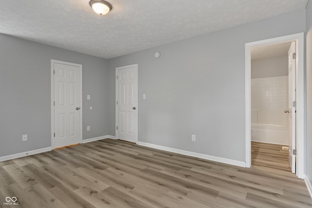 2359 Bremhaven Ct, Indianapolis, IN 46229 - unfurnished bedroom featuring light wood-style flooring, a textured ceiling, and ensuite bath