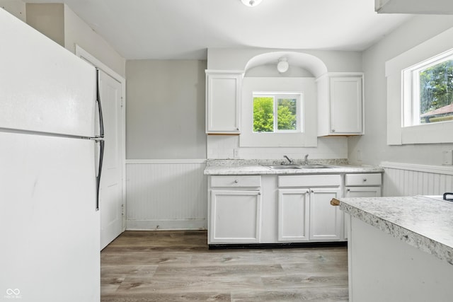 3424 Orchard Ave, Indianapolis, IN 46218 - kitchen featuring freestanding refrigerator, wainscoting, light countertops, white cabinetry, and light wood-type flooring