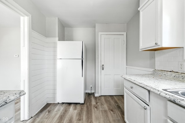 3424 Orchard Ave, Indianapolis, IN 46218 - kitchen with freestanding refrigerator, white cabinets, light wood-style flooring, a wainscoted wall, and light stone countertops