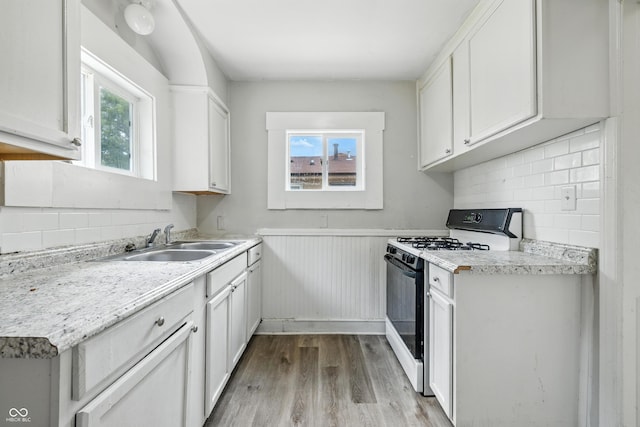3424 Orchard Ave, Indianapolis, IN 46218 - kitchen with gas stove, light wood-style floors, wainscoting, tasteful backsplash, and light countertops