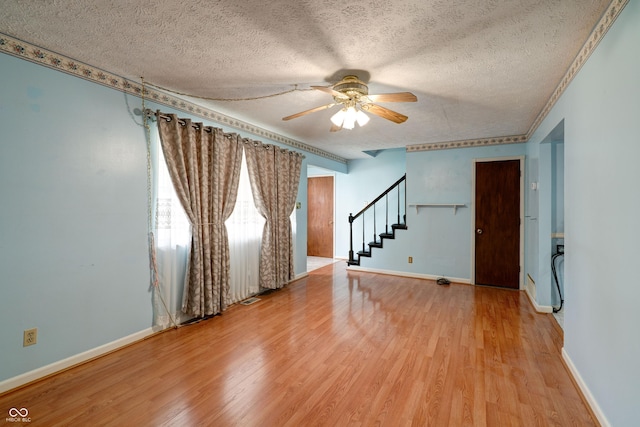5425 Gambel Rd, Indianapolis, IN 46221 - unfurnished room with a textured ceiling, ceiling fan, stairway, and light wood-style flooring