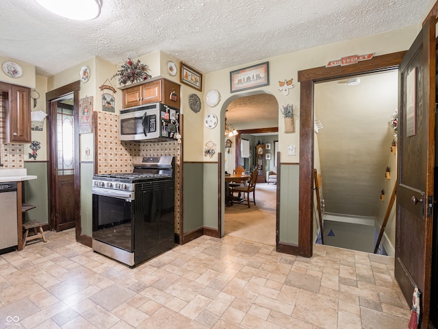 1556 E 400 S, Greenfield, IN 46140 - kitchen with appliances with stainless steel finishes, arched walkways, stone tile flooring, a textured ceiling, and light countertops