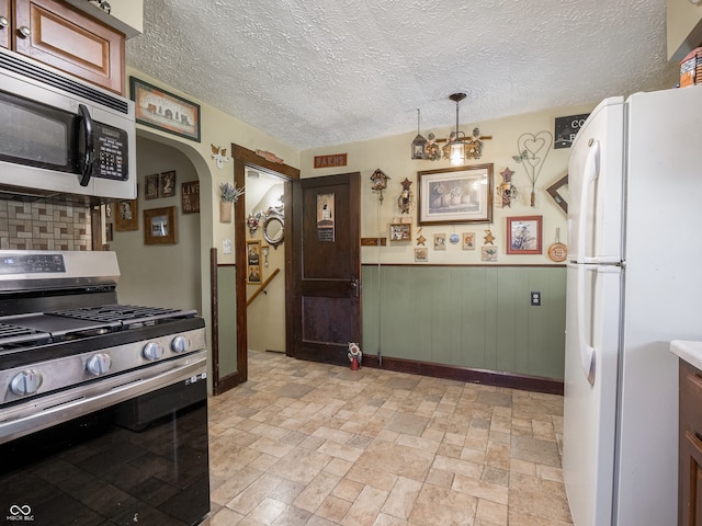1556 E 400 S, Greenfield, IN 46140 - kitchen with appliances with stainless steel finishes, arched walkways, tasteful backsplash, stone tile flooring, and a textured ceiling