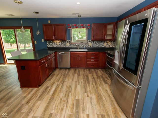 4443 W Windsong Ct, New Palestine, IN 46163 - kitchen featuring appliances with stainless steel finishes, a peninsula, light wood-style floors, dark countertops, and tasteful backsplash
