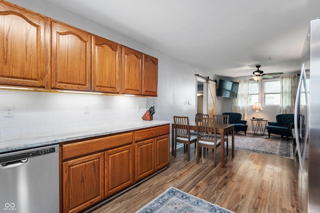 975 Locust St, Middletown, IN 47356 - kitchen featuring stainless steel appliances, wood finished floors, brown cabinetry, a barn door, and tasteful backsplash