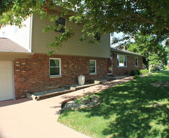 9808 E Troy Ave, Indianapolis, IN 46239 - view of side of home with a lawn, brick siding, an attached garage, and concrete driveway