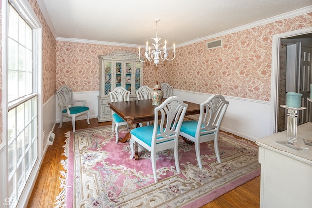 12602 Lockerbie Cir, Carmel, IN 46033 - dining room with wainscoting, a chandelier, wood finished floors, wallpapered walls, and crown molding