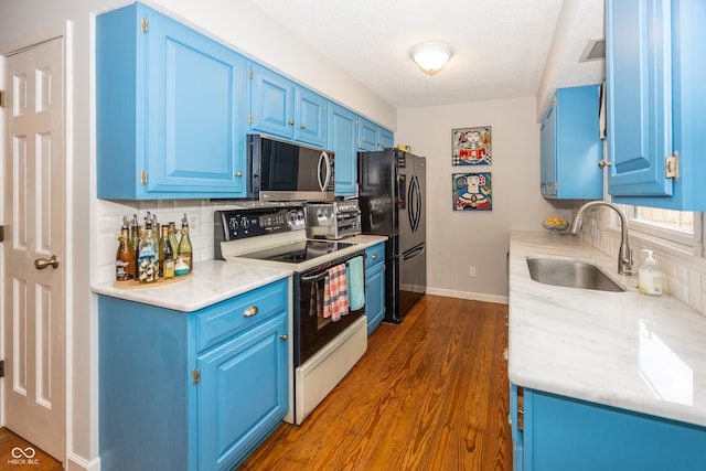 12602 Lockerbie Cir, Carmel, IN 46033 - kitchen featuring electric range oven, stainless steel microwave, freestanding refrigerator, blue cabinets, and decorative backsplash
