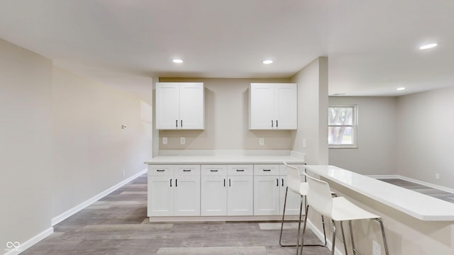830 Stardust Blvd, Noblesville, IN 46060 - kitchen with light countertops, white cabinetry, light wood-type flooring, recessed lighting, and a kitchen breakfast bar