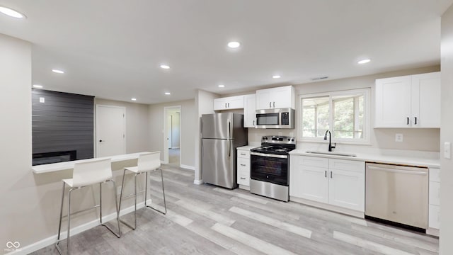 830 Stardust Blvd, Noblesville, IN 46060 - kitchen featuring stainless steel appliances, light wood-style flooring, white cabinets, light countertops, and a kitchen bar