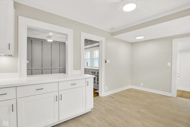 6711 Lafayette Rd, Indianapolis, IN 46278 - kitchen with ceiling fan, ornamental molding, white cabinets, light countertops, and light wood finished floors