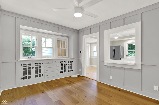 6711 Lafayette Rd, Indianapolis, IN 46278 - unfurnished room featuring a ceiling fan, a decorative wall, wood finished floors, and healthy amount of natural light