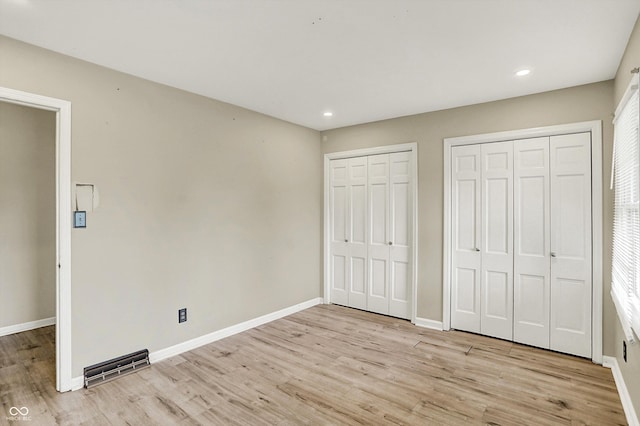 3302 Beech Dr, Columbus, IN 47203 - unfurnished bedroom with multiple closets, light wood finished floors, and recessed lighting