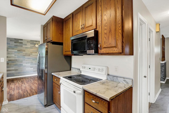 3302 Beech Dr, Columbus, IN 47203 - kitchen with white range with electric cooktop, brown cabinets, wallpapered walls, and freestanding refrigerator