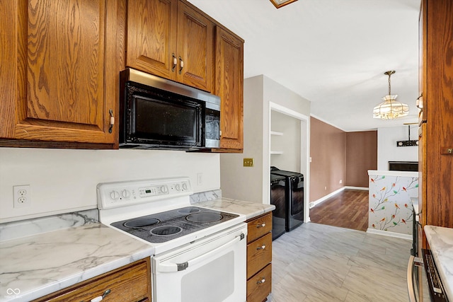 3302 Beech Dr, Columbus, IN 47203 - kitchen featuring black microwave, white electric range oven, brown cabinets, washer and dryer, and hanging light fixtures