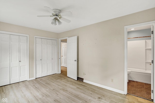 3302 Beech Dr, Columbus, IN 47203 - unfurnished bedroom featuring light wood finished floors, multiple closets, ensuite bathroom, and ceiling fan