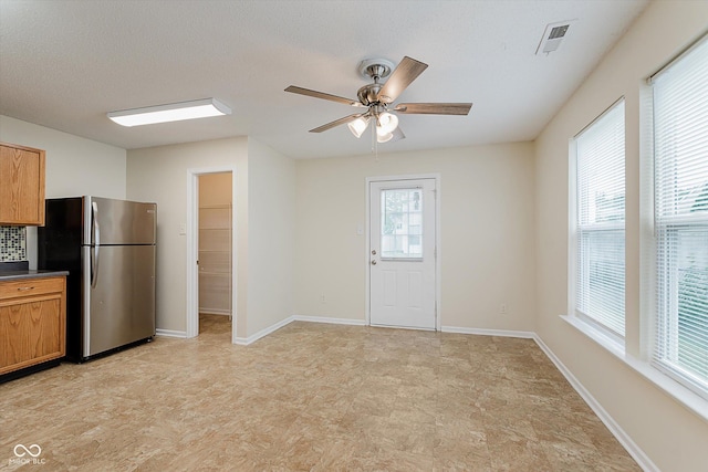 3183 Hemlock St, Whiteland, IN 46184 - kitchen with freestanding refrigerator, ceiling fan, dark countertops, brown cabinetry, and light flooring